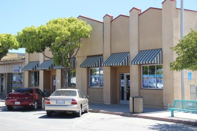 A downtown street with cars parked in front of a business.
