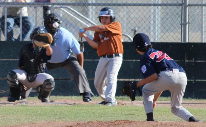 A kid playing baseball swinging at a pitch.