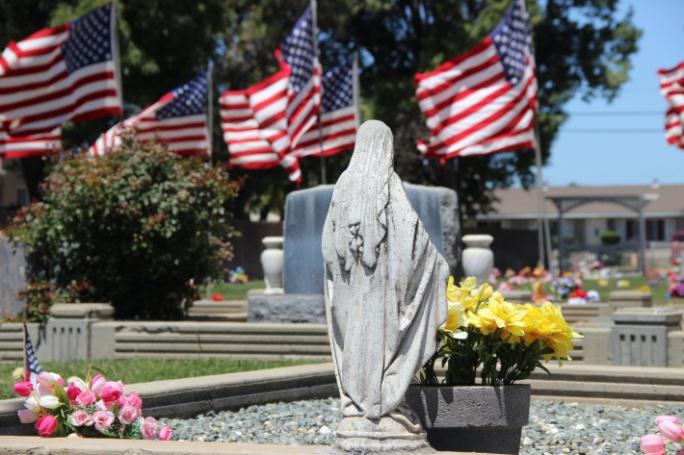 A grave monument with American flags in the background.