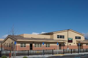 A tan and brown building surrounded by a black fence.