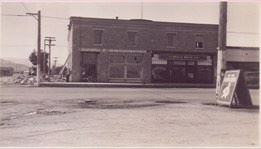 A black and white photo of a store on the corner.