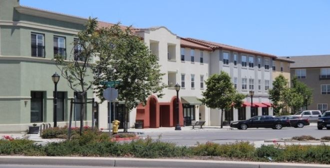 Buildings on a street with cars parked in front.